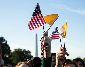 Begrüßungszeremonie für Papst Franziskus im South Lawn des Weißen Hauses am 23. September 2015 in Washington. Bild: Eine Frau hält einen Rosenkranz, die Fahne des Vatikans und der USA in die Höhe.
